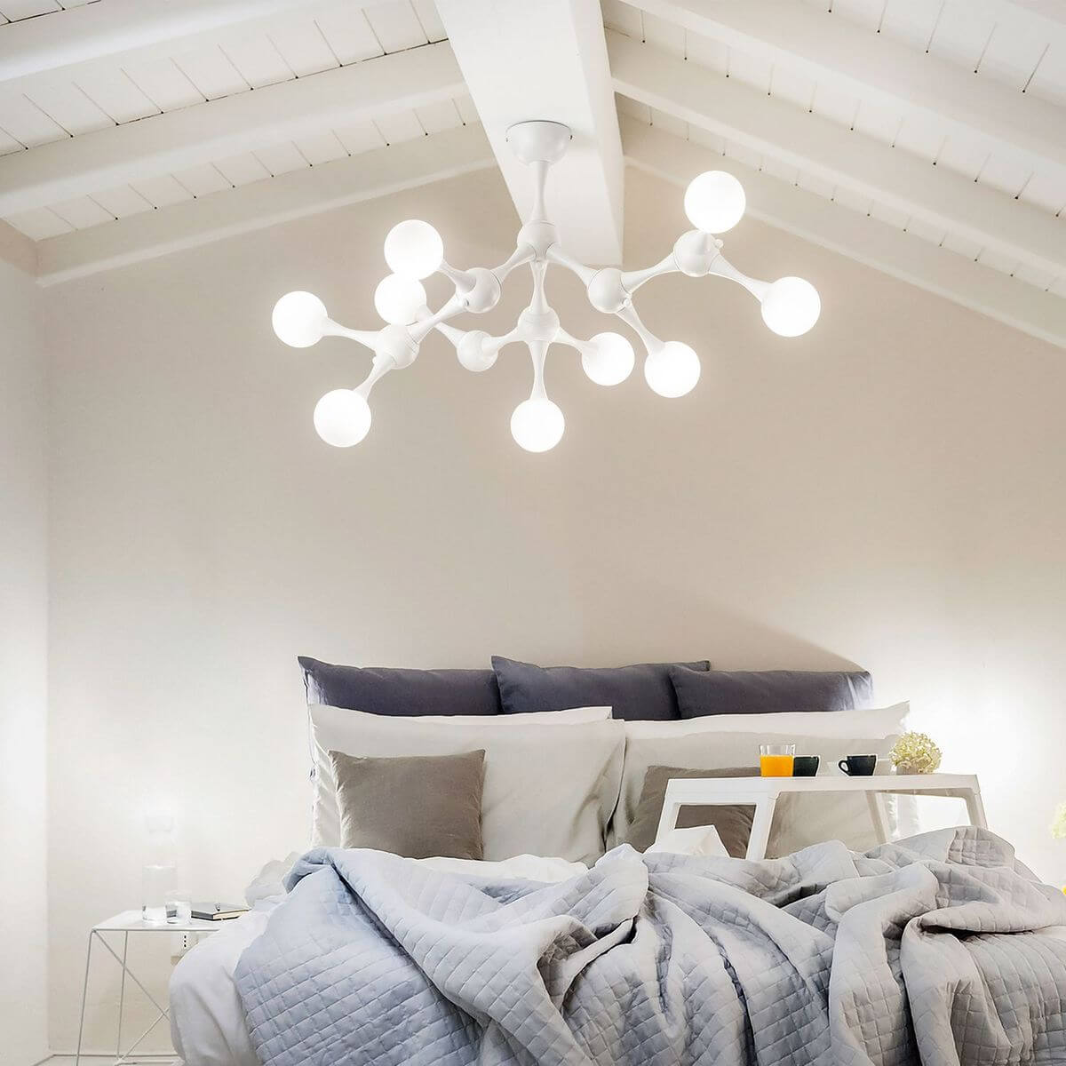 Luminaire allumé au plafond d'une chambre au-dessus d'un lit à coussins