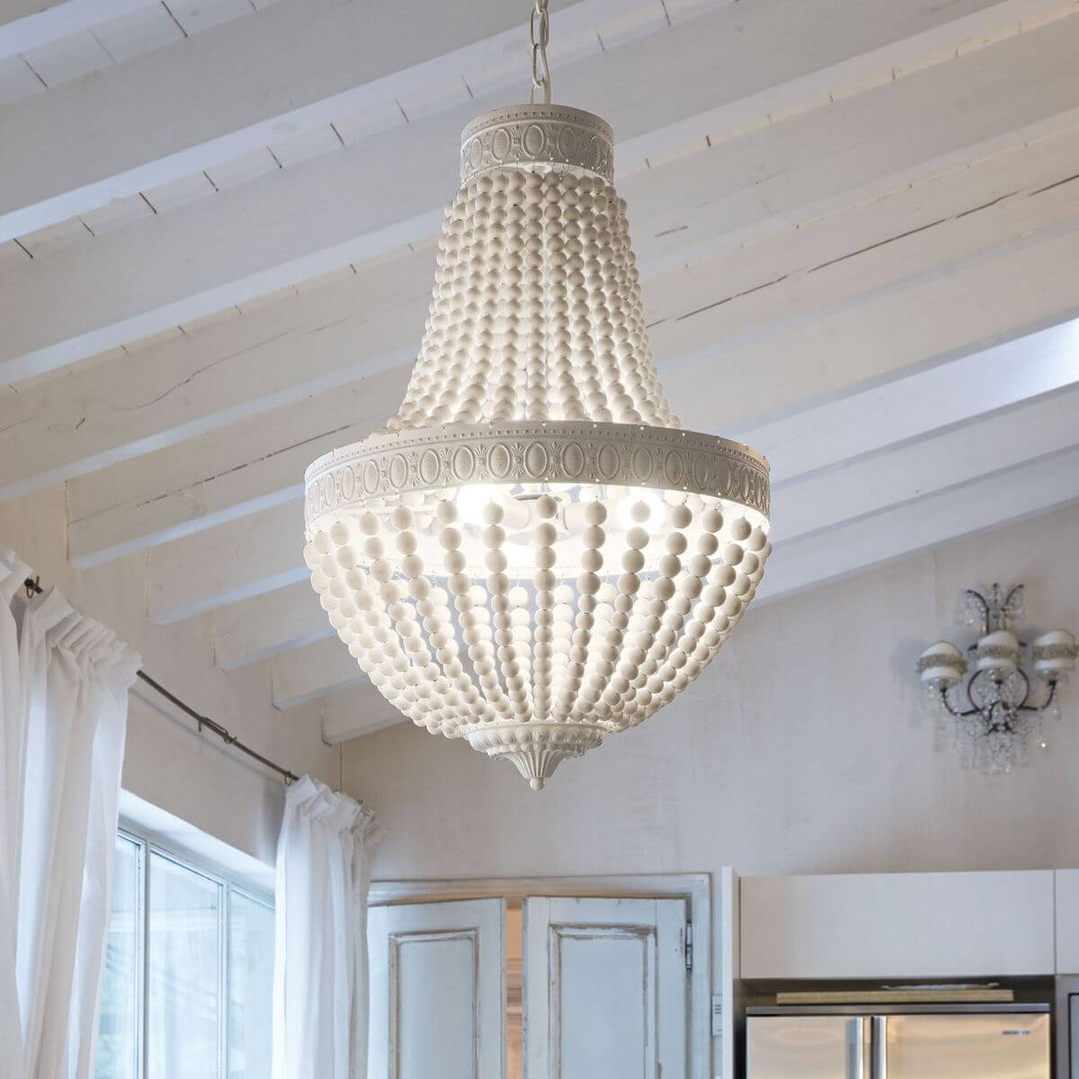 Luminaire suspendu allumé sous un plafond à poutres blanches, ambiance de cuisine
