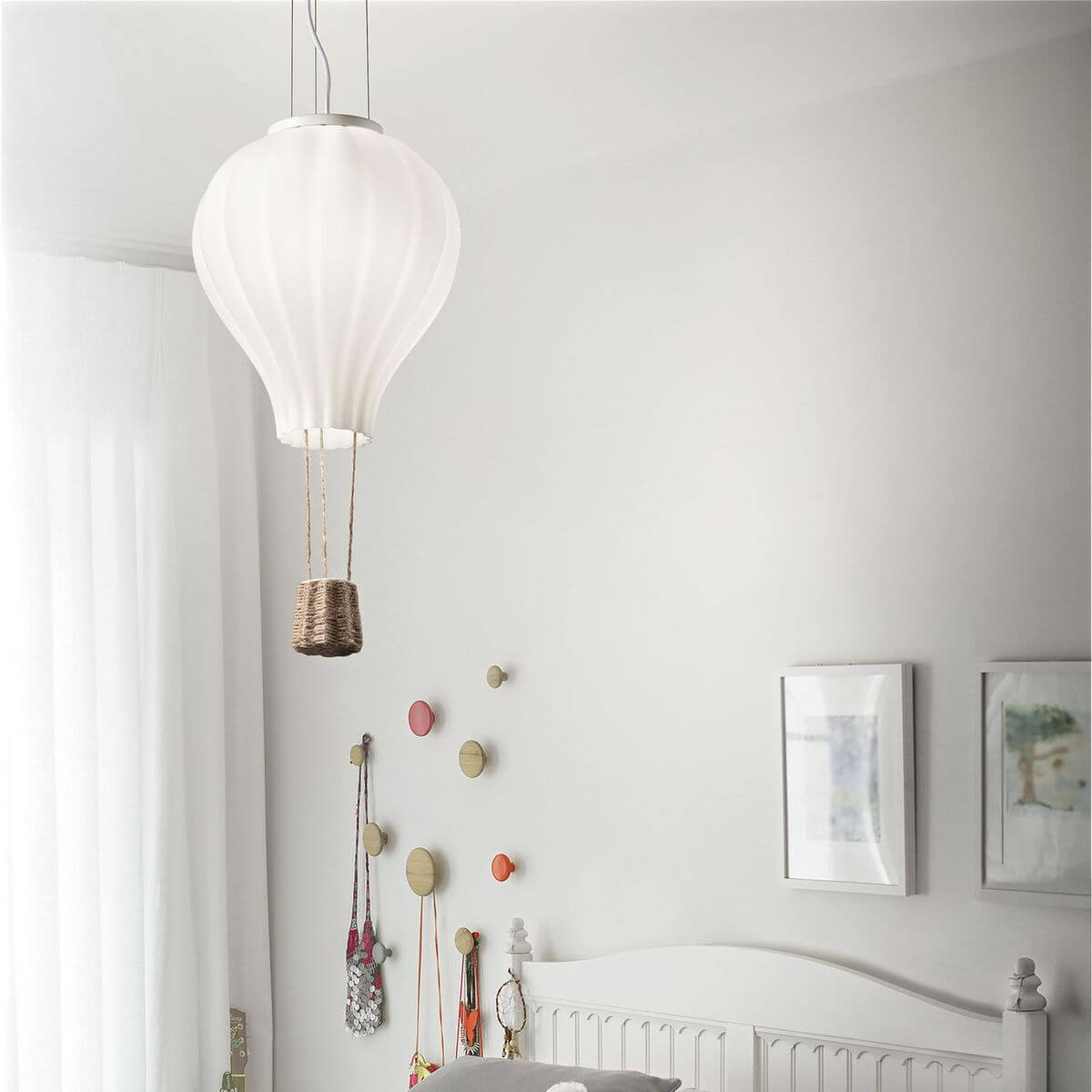 Luminaire suspendu au-dessus d'un lit d'enfant dans une chambre blanche et lumineuse.