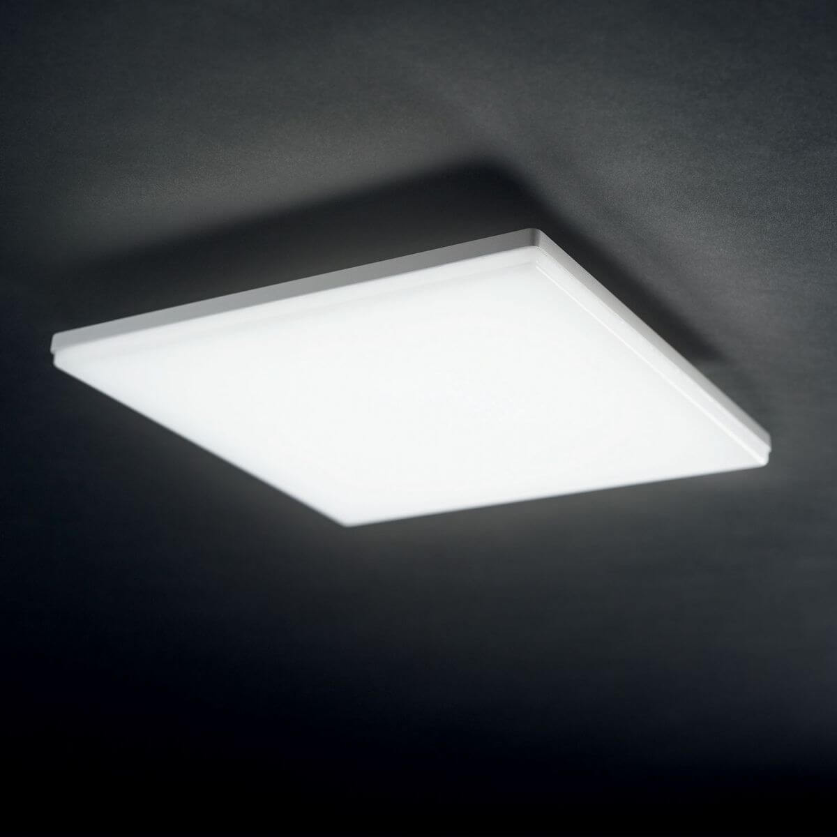 Plafonnier carré allumé, fixé sous un plafond sombre, lumière diffuse
