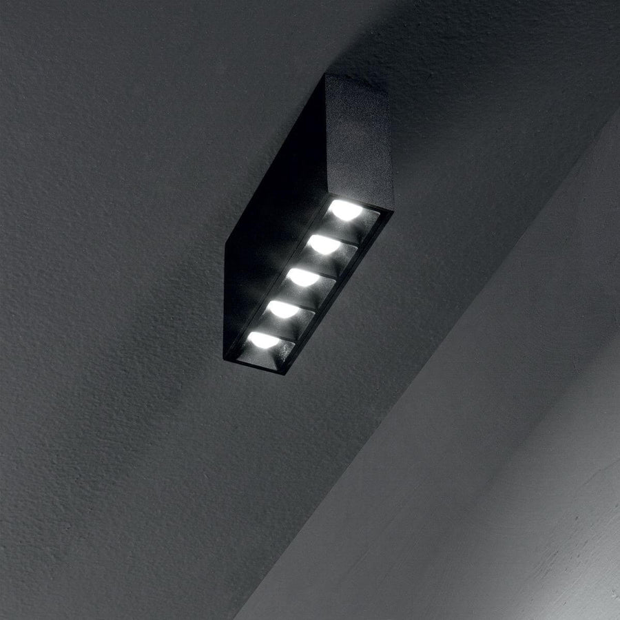 Plafonnier noir installé au plafond, cinq LED allumées en situation sombre