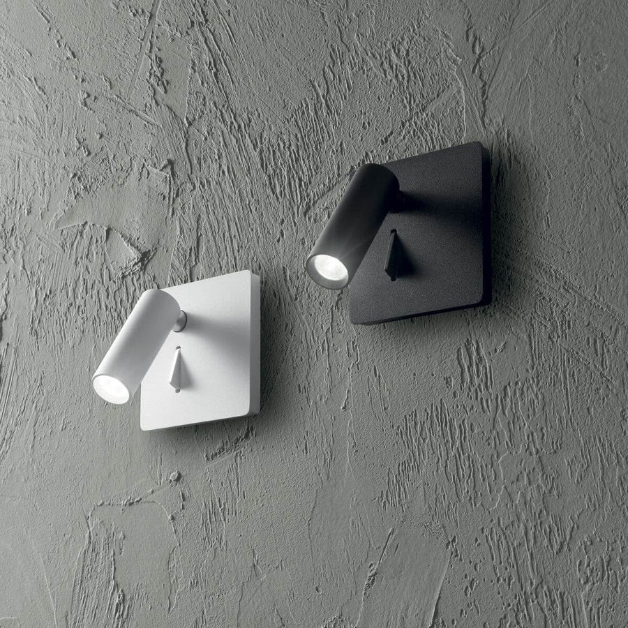 Deux appliques murales blanche et noire fixées sur un mur gris texturé.