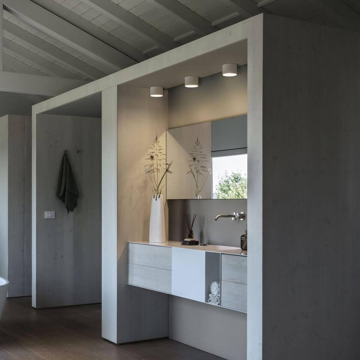 Mise en ambiance de trois plafonniers alignés au-dessus d'un miroir de salle de bain