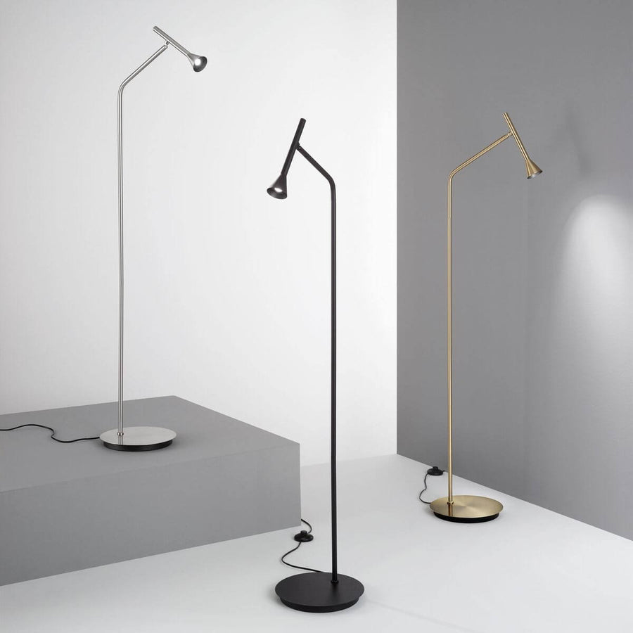 Trois lampadaires noirs, chromés et dorés présentés en situation dans un intérieur gris