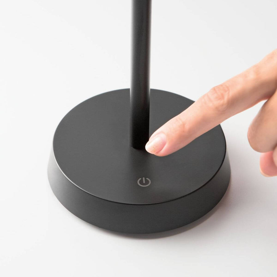Détail du socle noir avec un doigt appuyant sur le bouton tactile