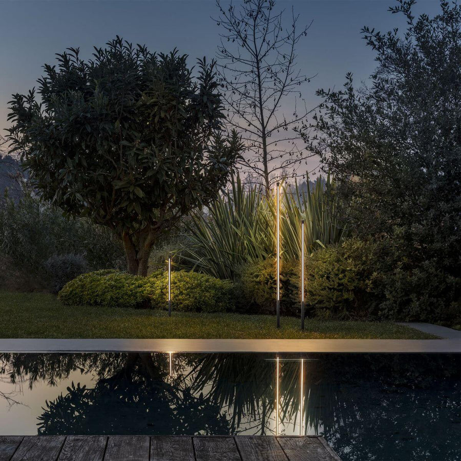 Deux lampadaires illuminés au bord d'une piscine, reflets dorés au crépuscule