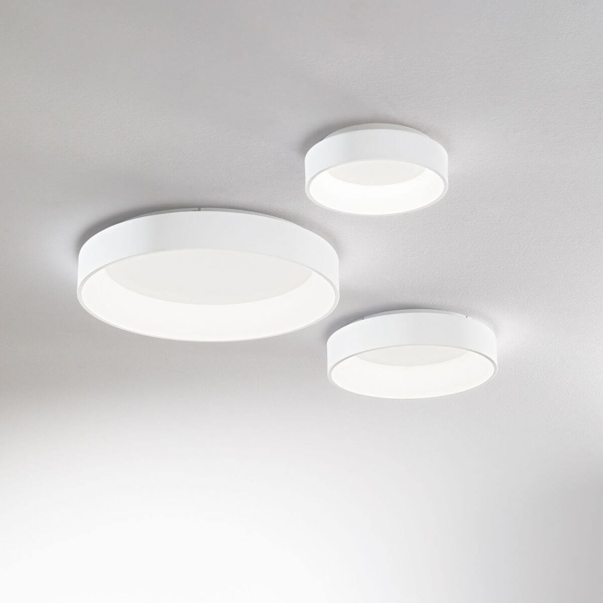 Trois plafonniers blancs de tailles différentes fixés au plafond gris