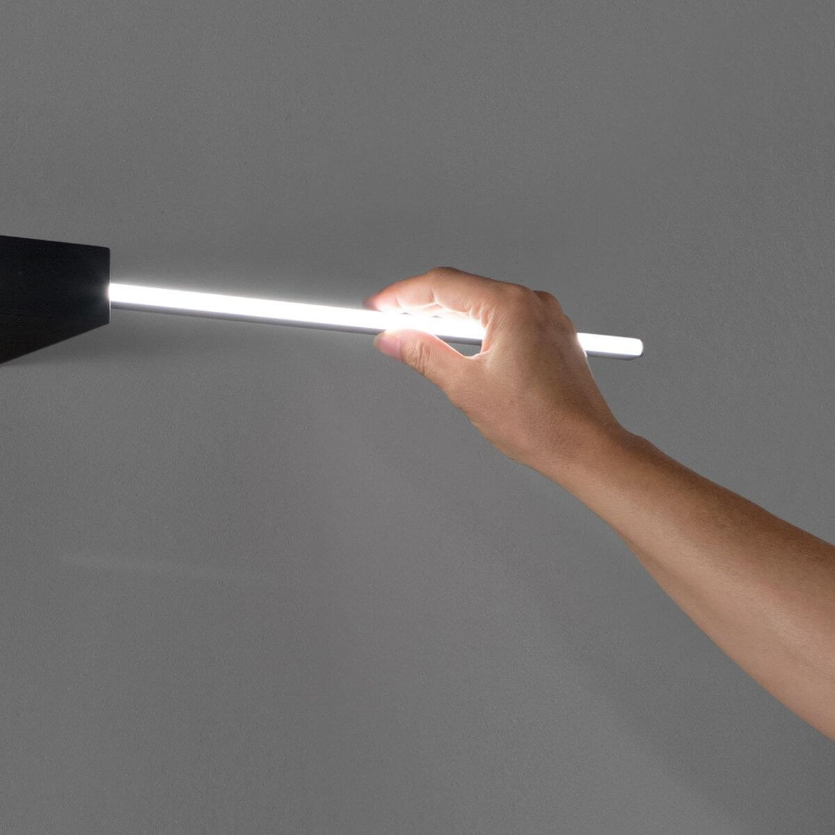 Main tenant le tube lumineux allumé, montrant le diffuseur et la lumière produite.