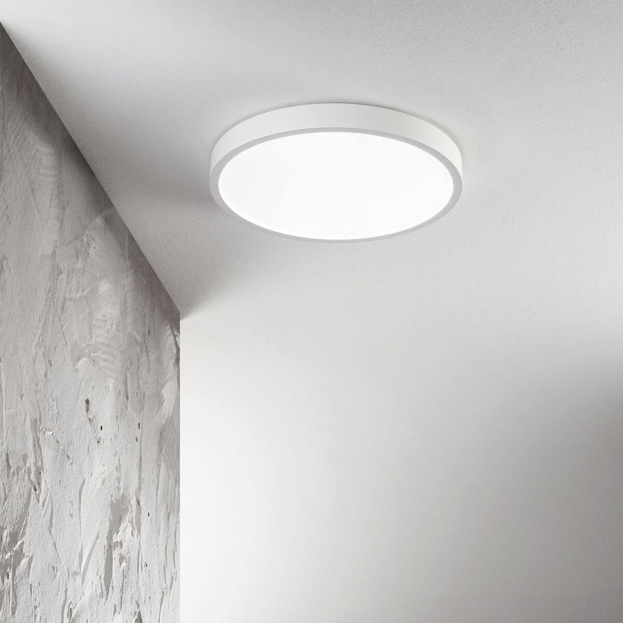 Luminaire blanc fixé au plafond près d'un mur texturé, lumière allumée