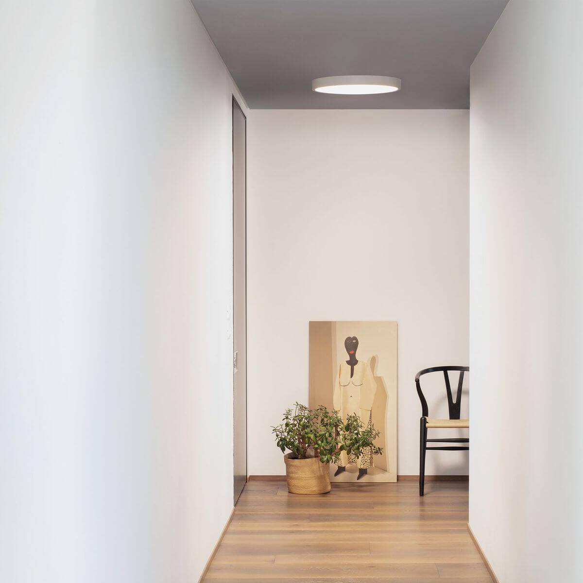 Vue d'ensemble d'un couloir clair avec plafonnier rond blanc allumé