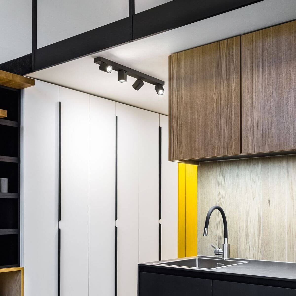 Mise en ambiance dans une cuisine moderne, luminaire noir fixé au plafond au-dessus du plan de travail