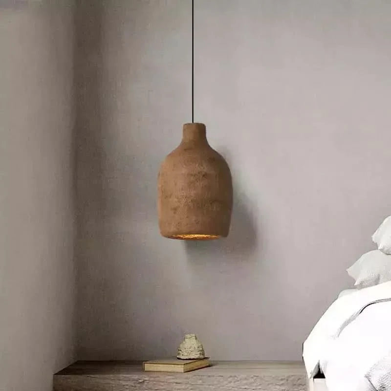 Suspension style pierre marron au-dessus d'une table de chevet en bois dans une chambre epuree