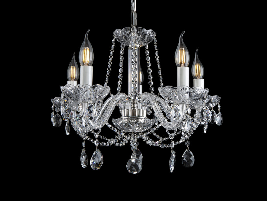 Lustre en cristal à cinq bras vu de face sur fond noir, ampoules allumées