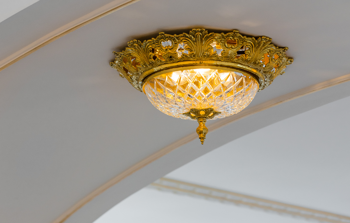 Plafonnier doré installé au plafond, allumé, lumière chaude ambrée