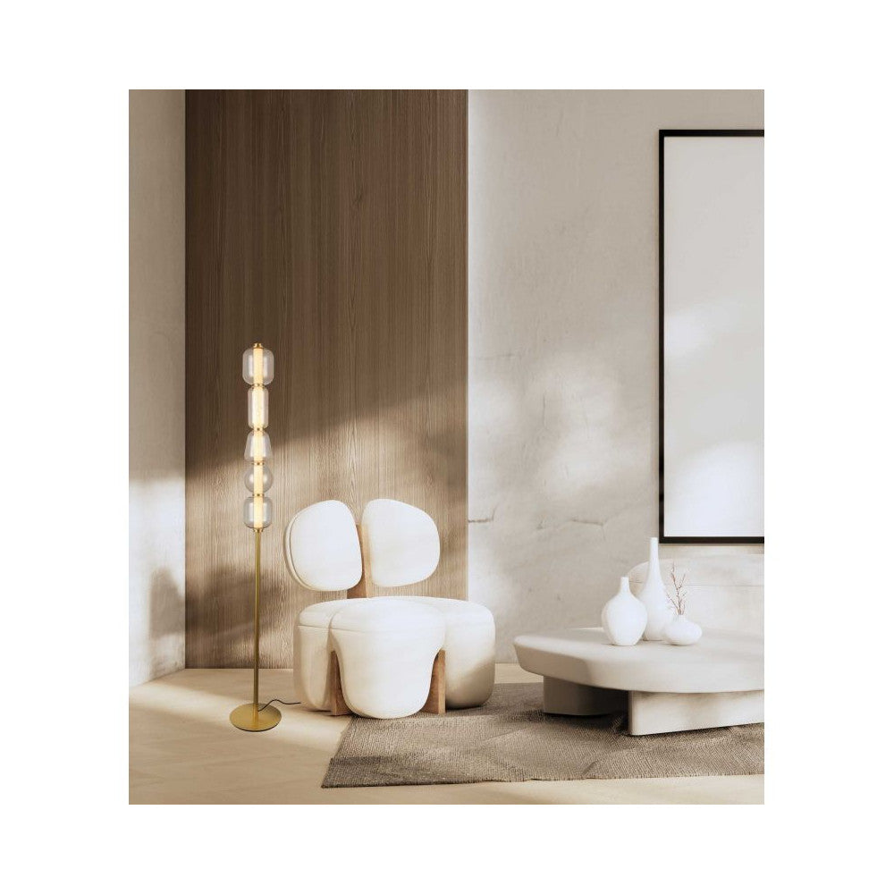 Lampe sur pied allumée dans un salon moderne, près d'un fauteuil blanc et d'une table basse.