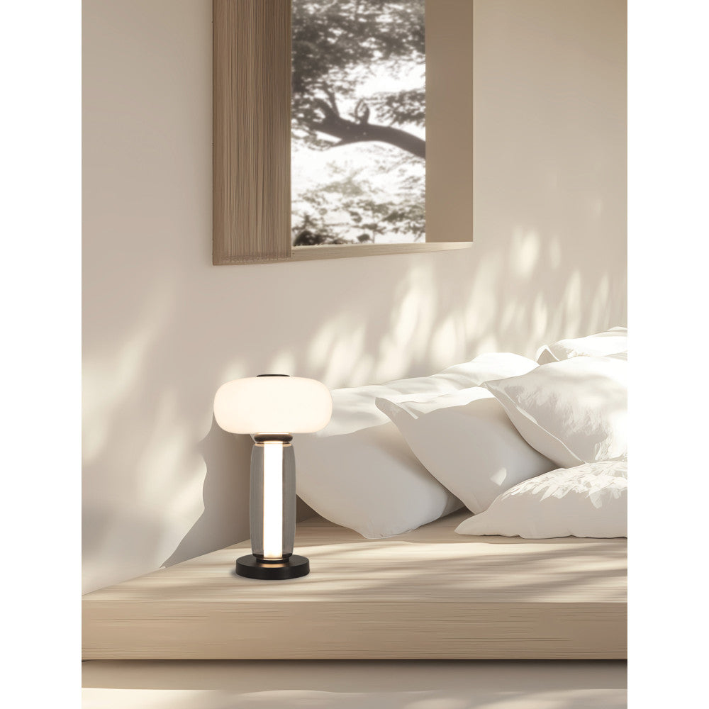 Mise en ambiance chambre, lampe posée près de coussins blancs, ombres végétales au mur