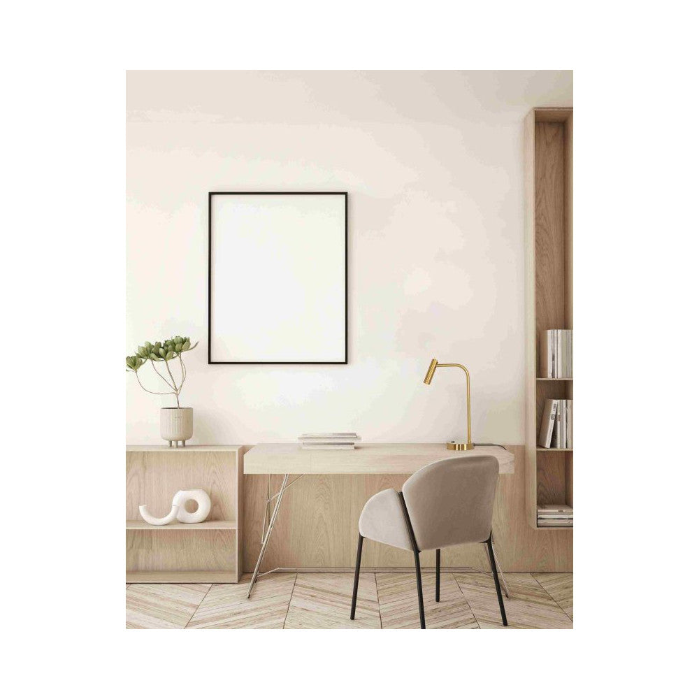 Mise en ambiance sur un bureau en bois clair avec cadre vide au mur.