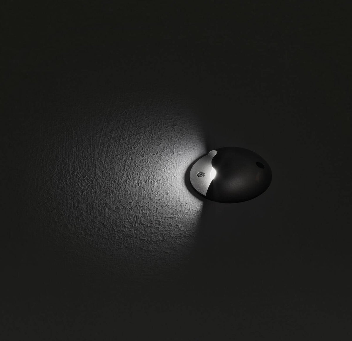 Mise en ambiance nocturne du luminaire encastré éclairant une surface texturée.