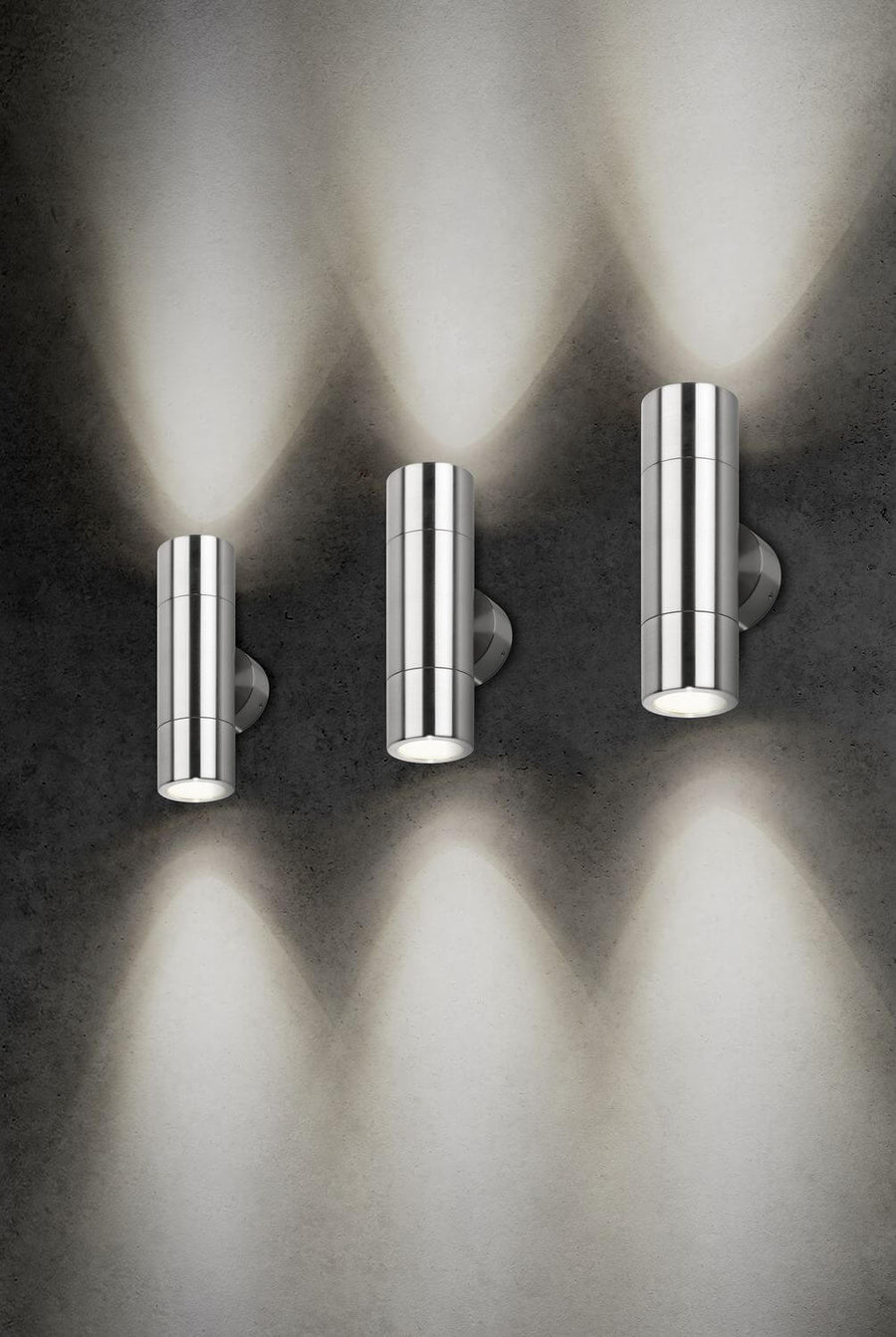 Trois luminaires muraux cylindriques en inox avec faisceaux lumineux verticaux
