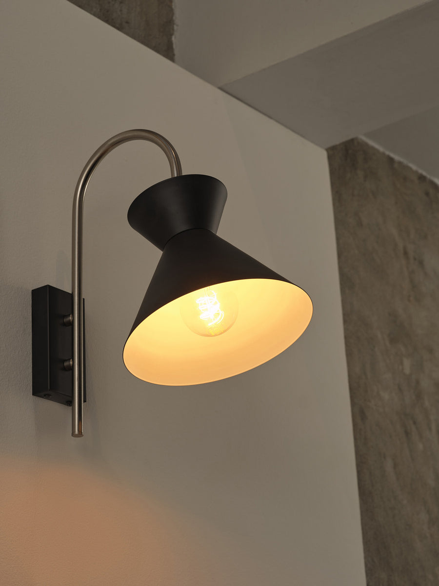 Gros plan sur l'abat-jour noir allumé, dévoilant l'ampoule à filament à l'intérieur.