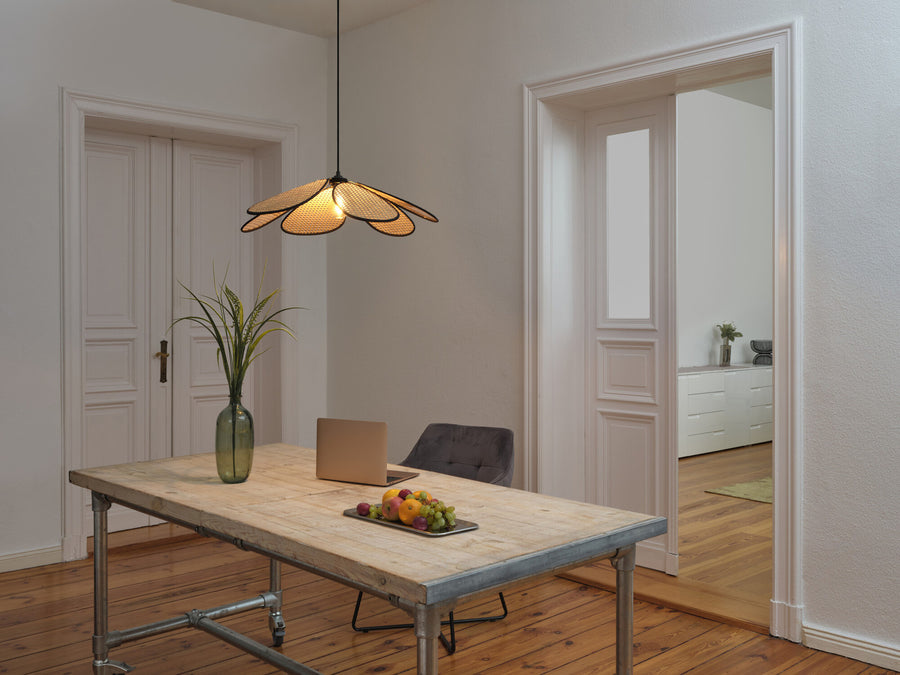 Suspension en cannage allumée au-dessus d'une table en bois rustique.