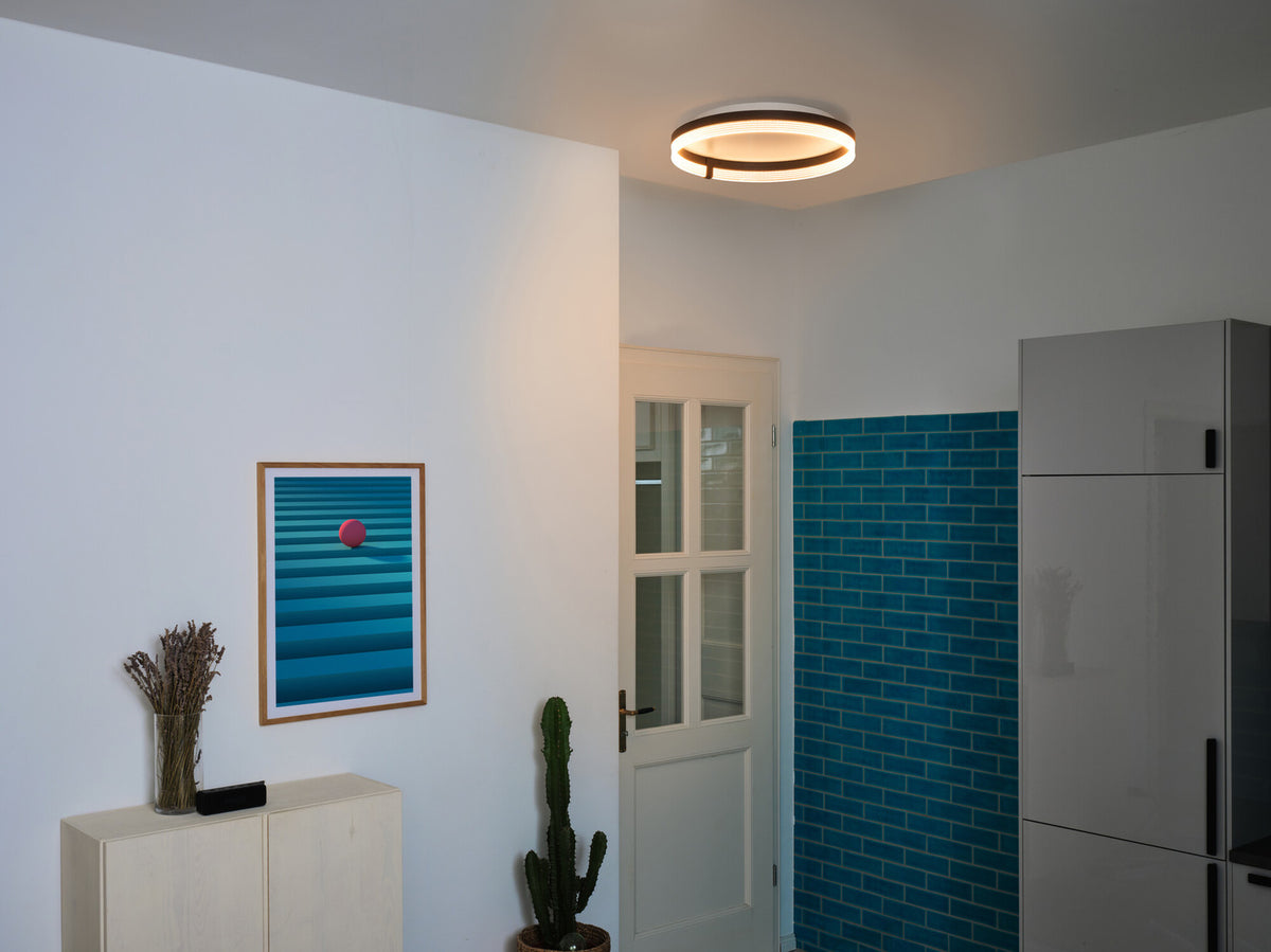 Le plafonnier allumé en lumière chaude dans le même couloir d’entrée.