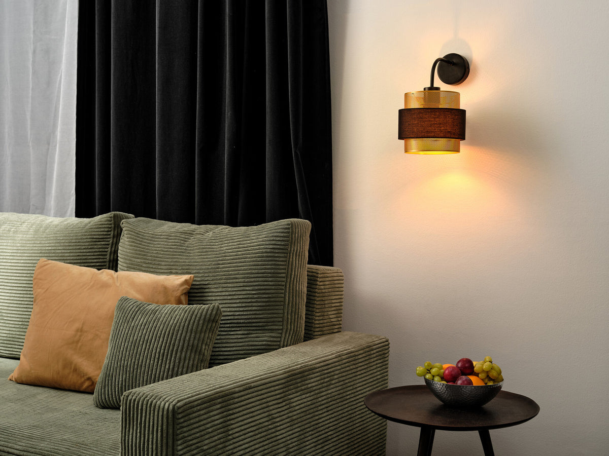 Applique allumée fixée au mur au-dessus d'un canapé vert et d'un coussin orange