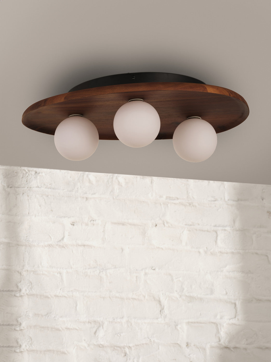Vue rapprochée du luminaire fixé au plafond devant un mur en briques blanches.