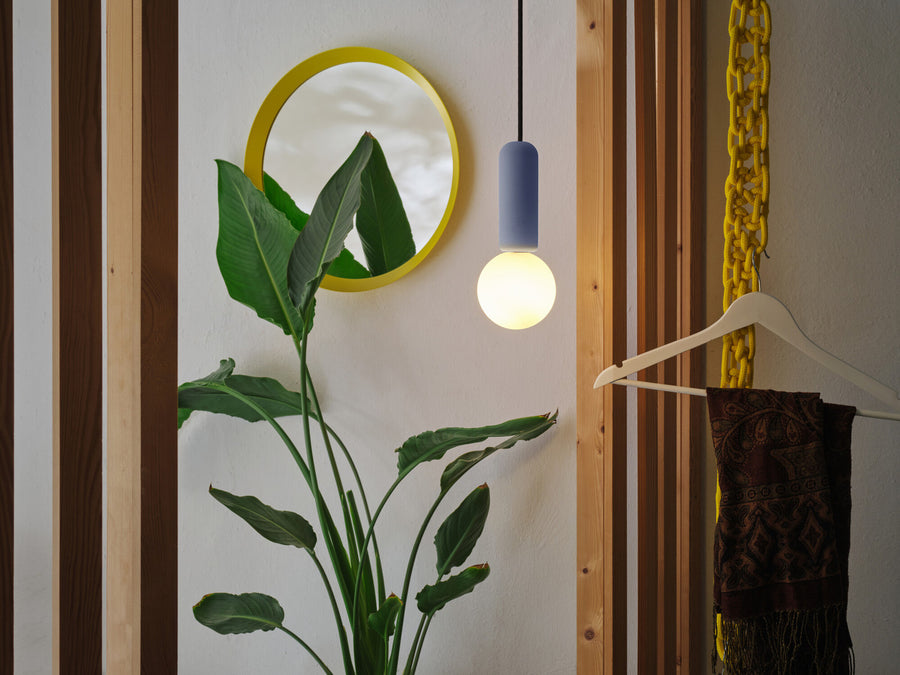 Suspension allumée dans une entrée déco avec miroir jaune et plante