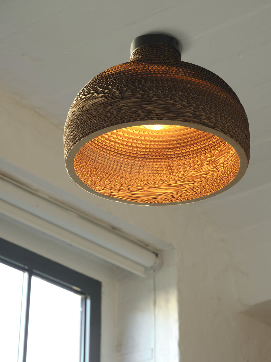 Vue en contre-plongée du plafonnier allumé, dévoilant l'intérieur ondulé et lumineux.