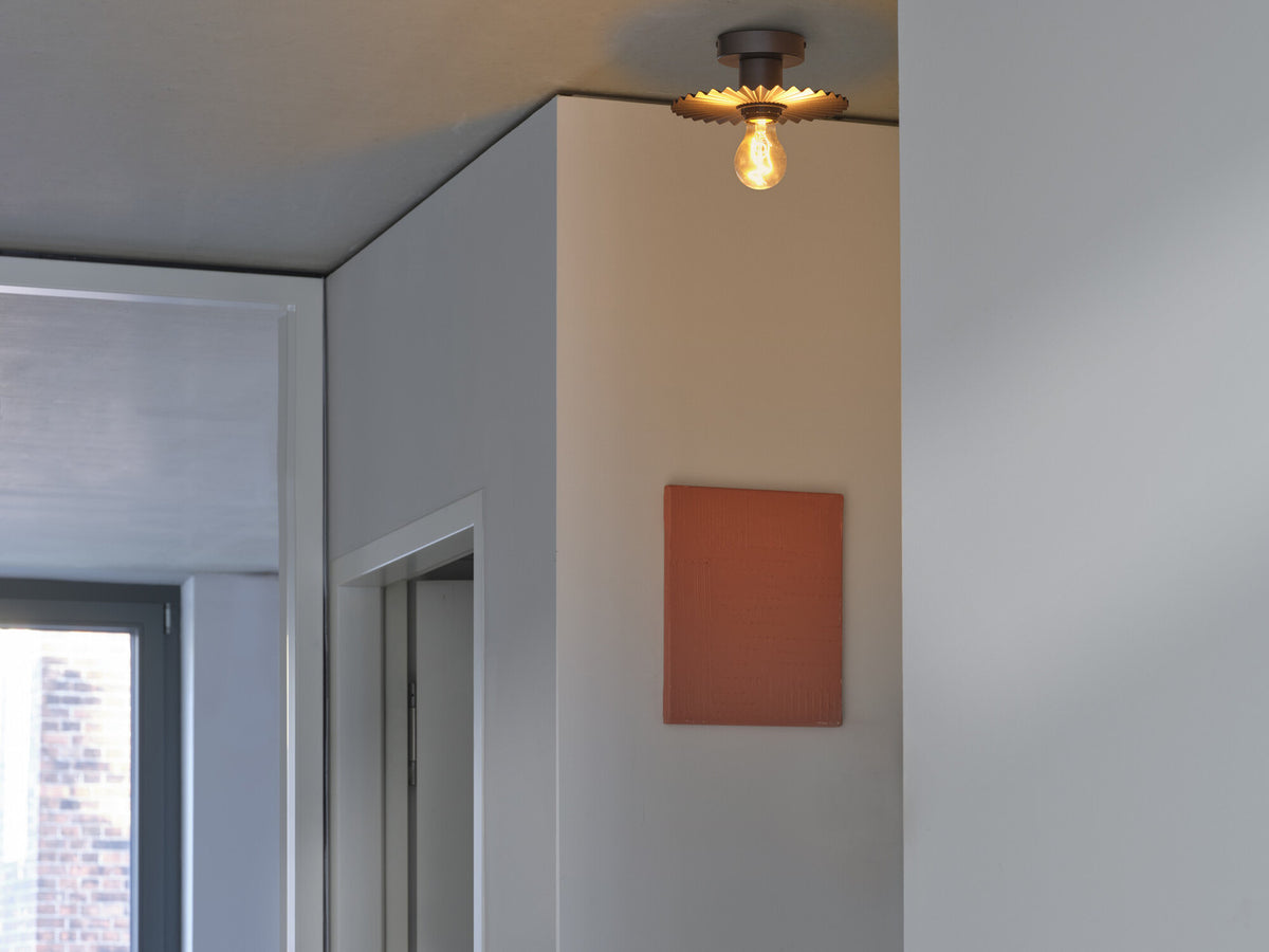 Plafonnier installé au plafond dans un coin, ampoule allumée et mur clair.