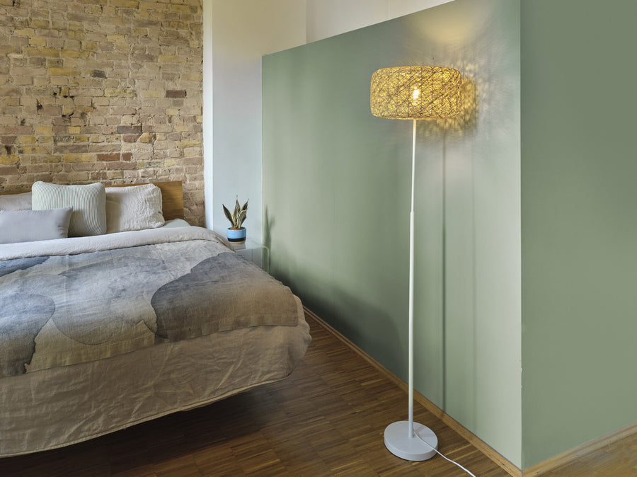 Lampadaire allumé près d'un lit dans une chambre au mur vert