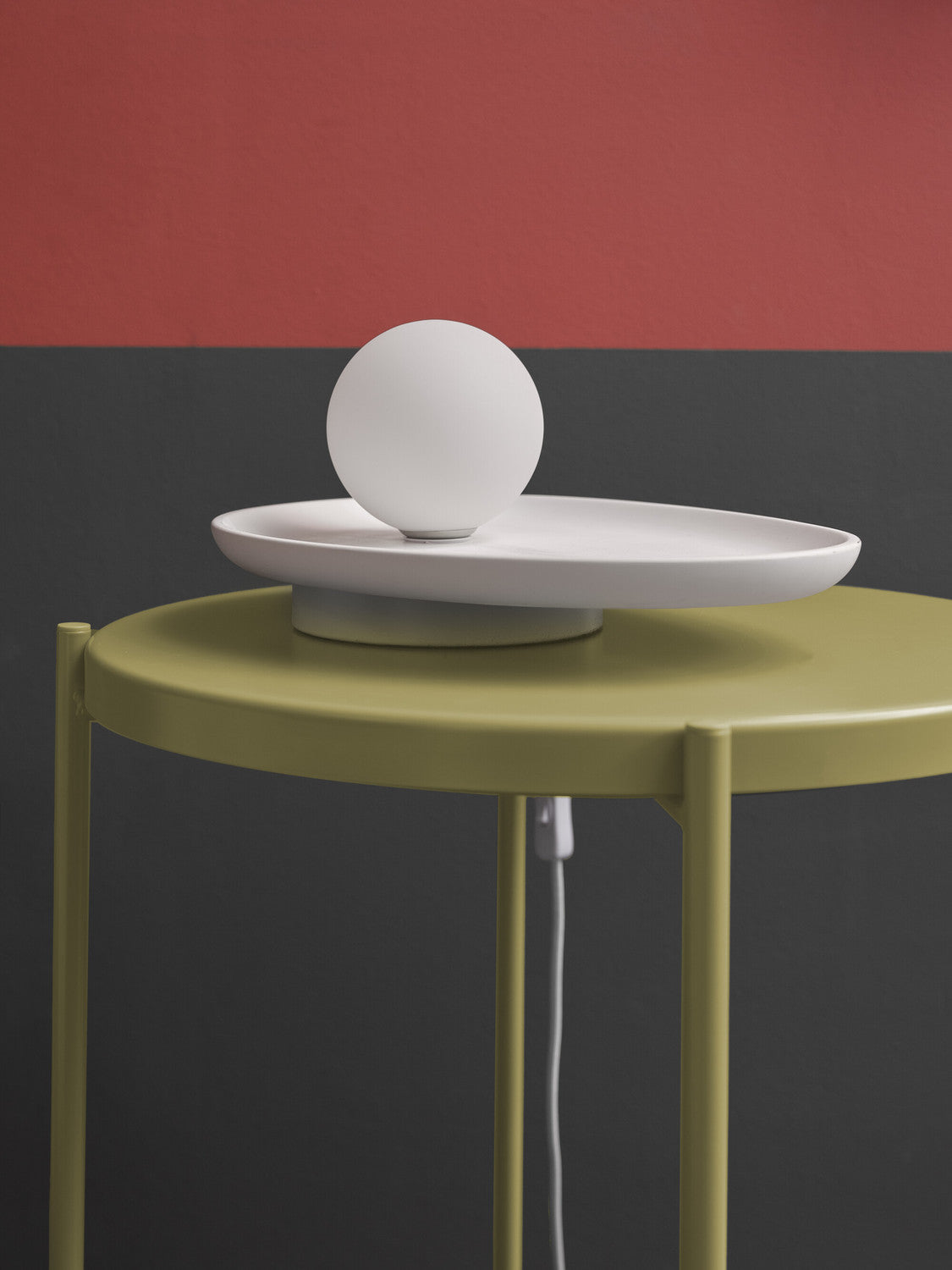 Détail du globe blanc éteint et du plateau ovale sur table vert olive