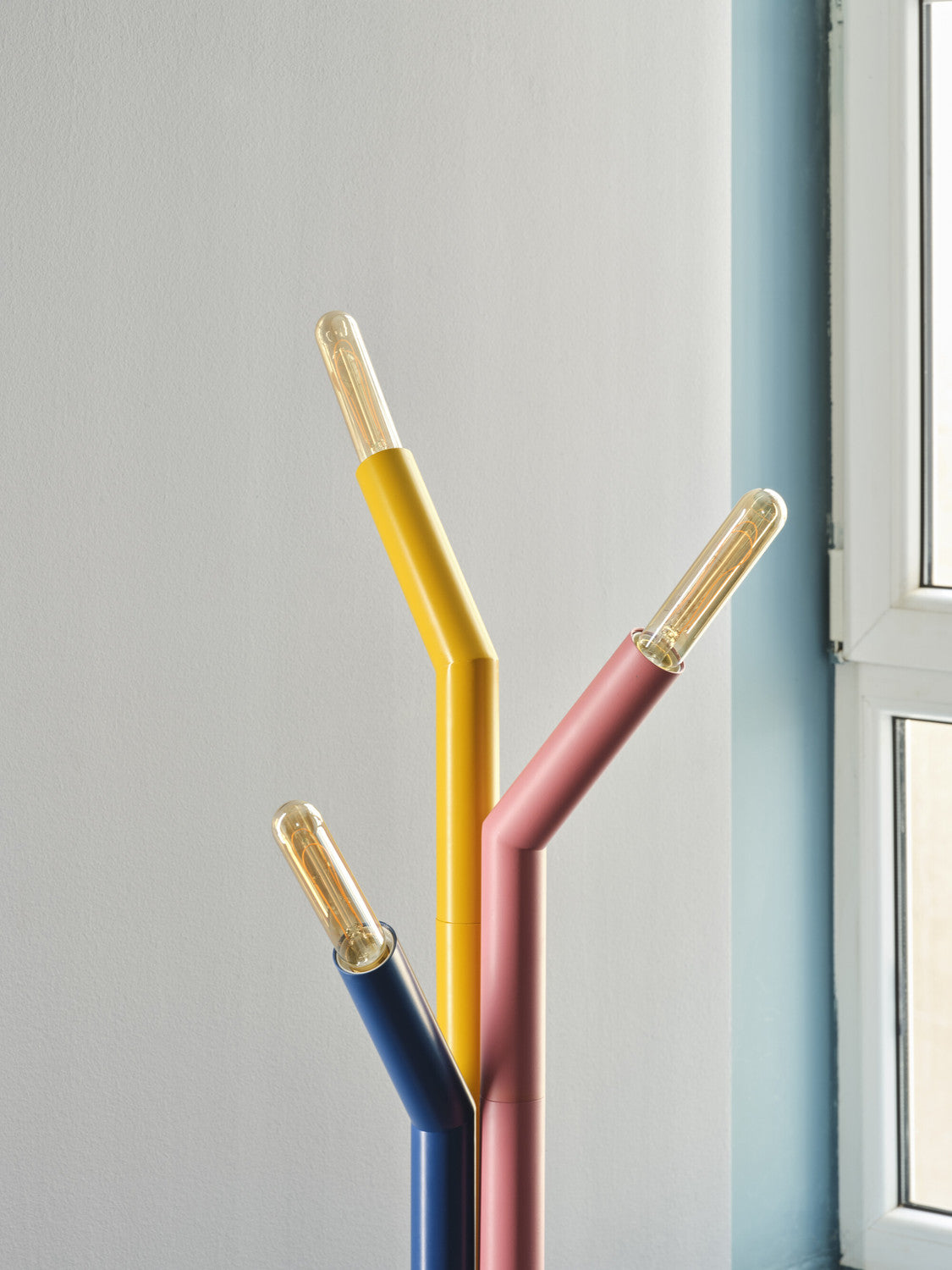 Détail des trois tiges colorées et des ampoules transparentes allumées du lampadaire.