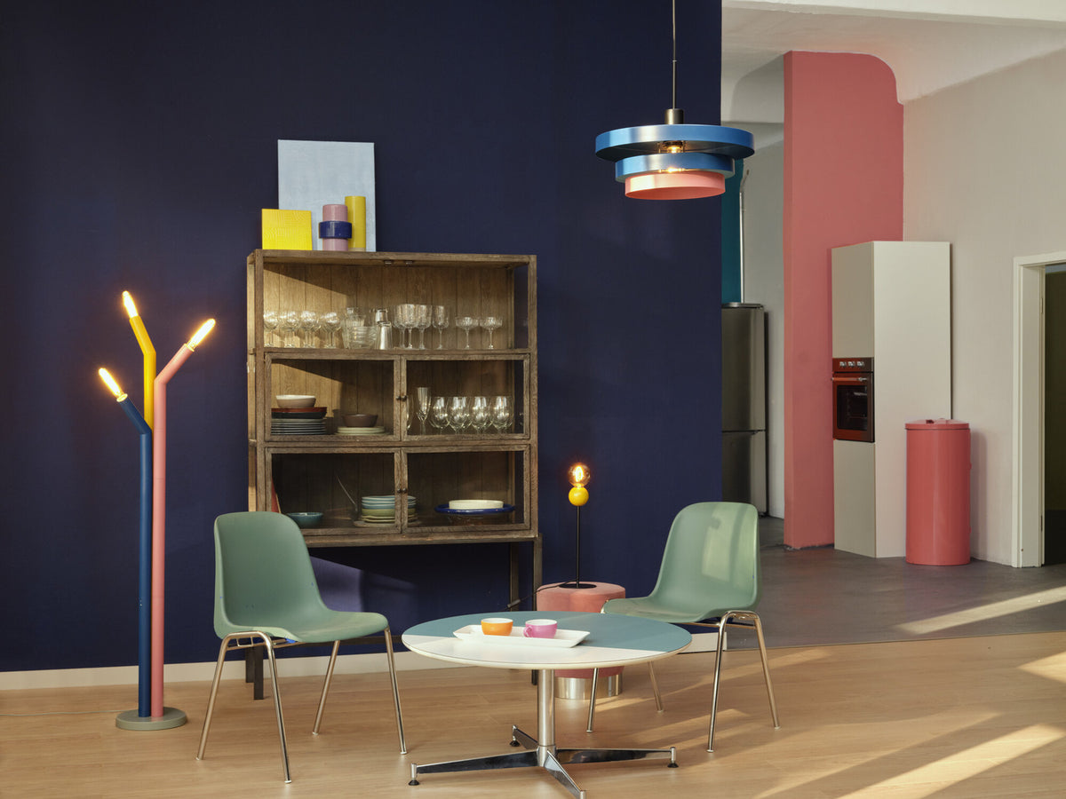 Lampadaire coloré et suspension bleue et rose dans une pièce au mur bleu nuit.