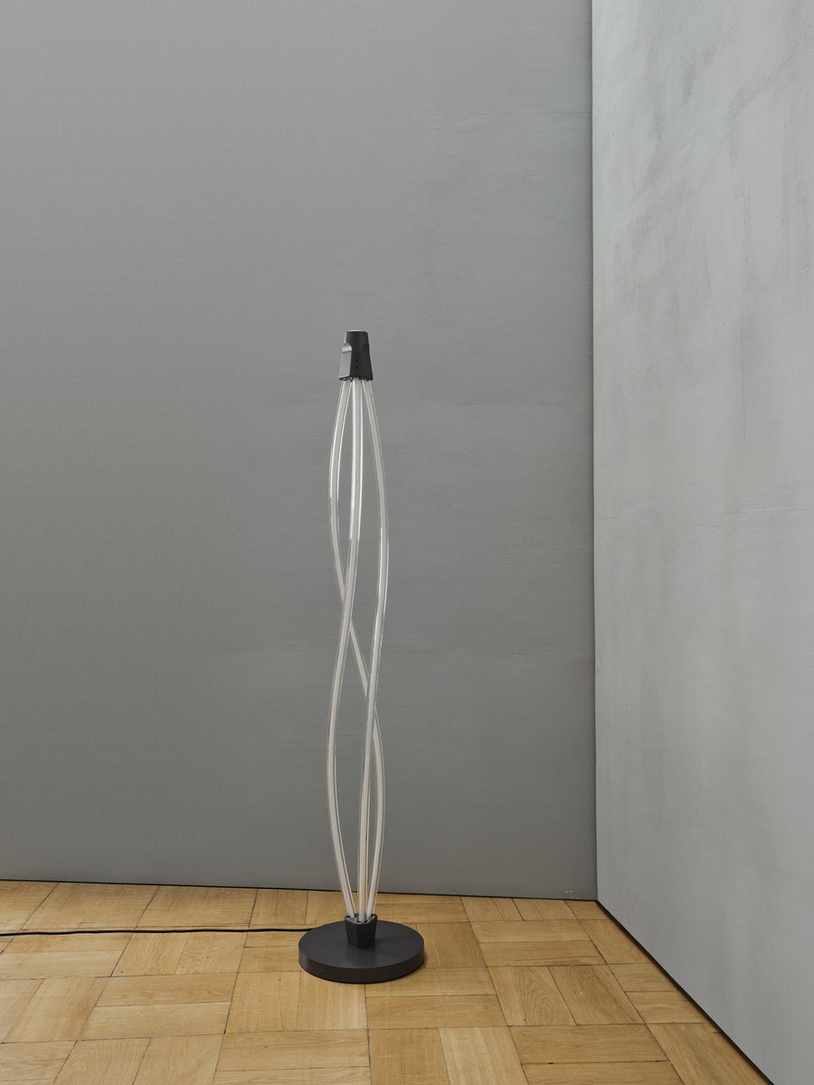 Lampadaire Swirl éteint dans un coin, base noire sur parquet clair.