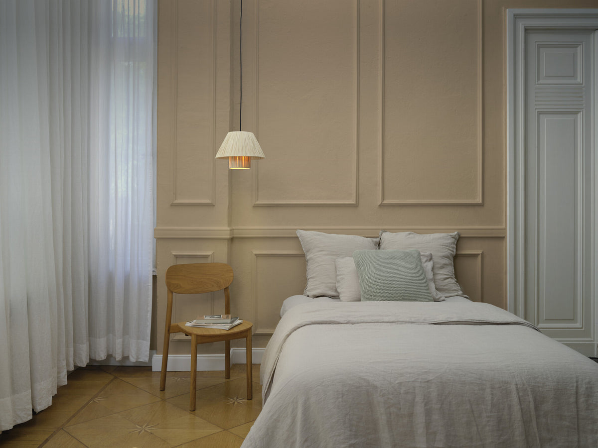 Mise en ambiance dans une chambre, suspension allumée au-dessus de la table de chevet