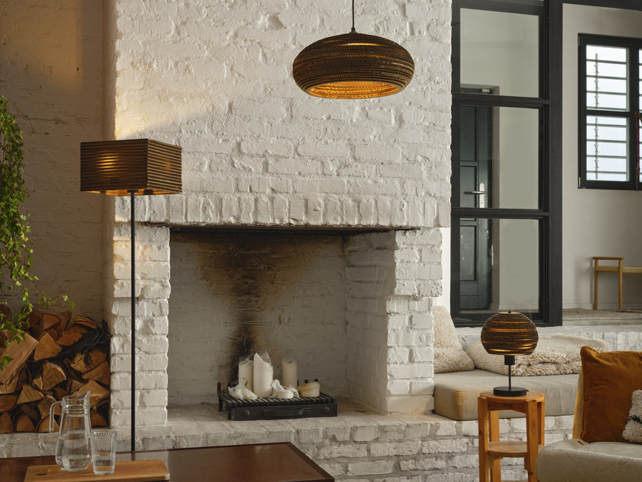 Ambiance cheminée blanche, suspension en carton allumée au-dessus du foyer, bois et bougies