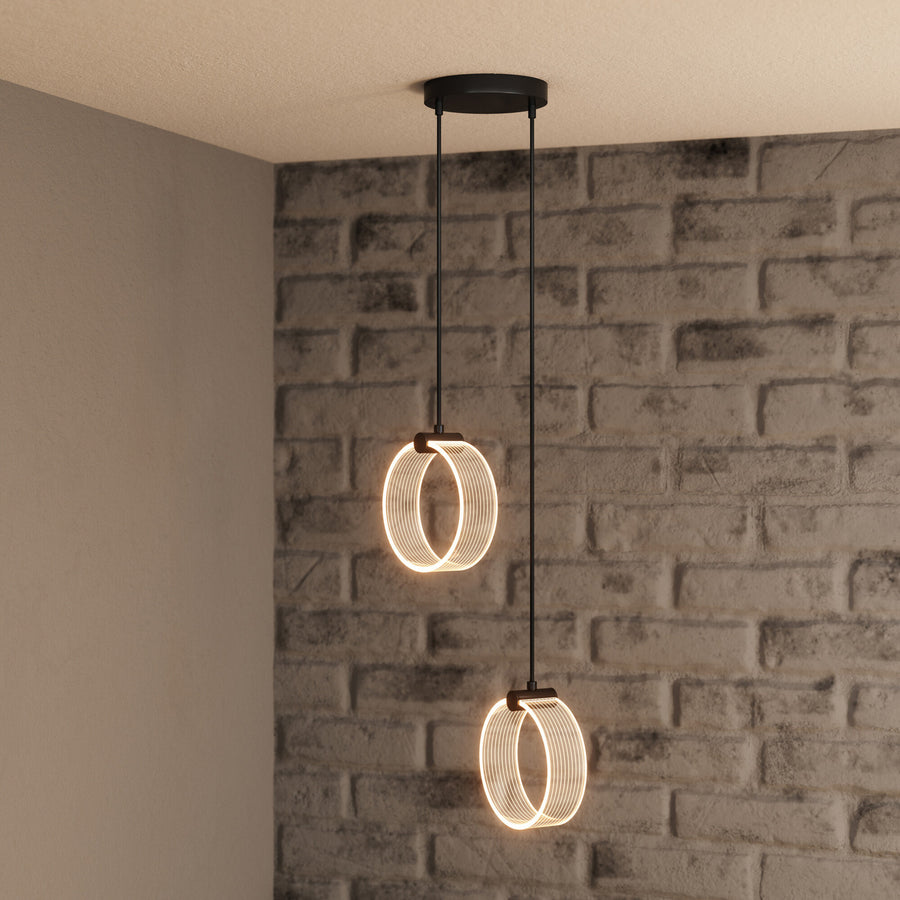 Détail de deux anneaux lumineux suspendus devant un mur de briques, lumière chaude.