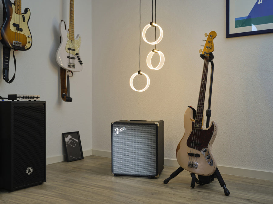 Trois anneaux lumineux suspendus devant un mur blanc et des instruments