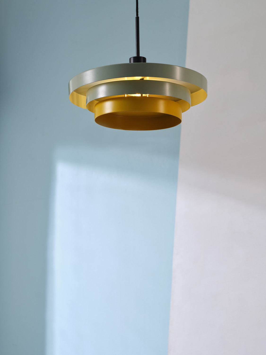 Vue rapprochée de la suspension allumée projetant une lumière chaude sur le mur.