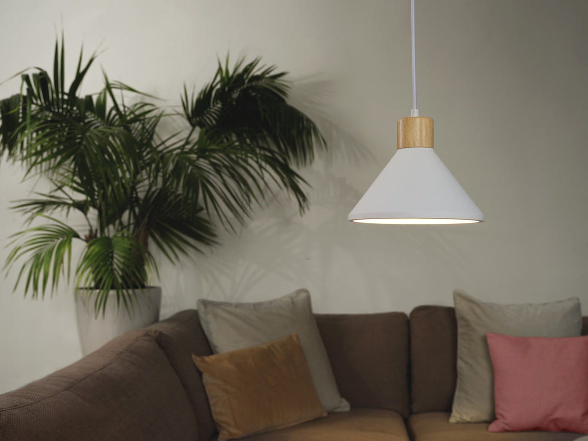 Mise en ambiance salon avec suspension blanche allumée au-dessus d’un canapé et d’une plante.