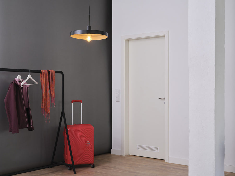 Suspension plate noire installée dans une entrée avec portant et valise.