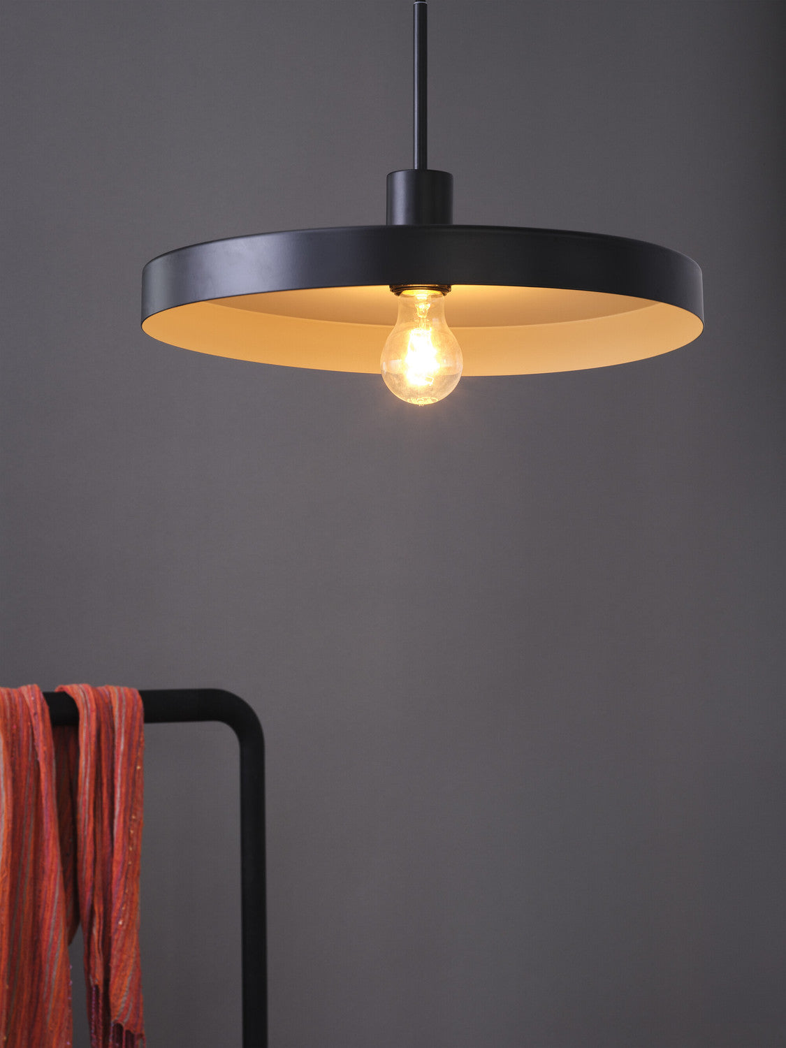 Gros plan sur la suspension noire allumée avec ampoule à filament.