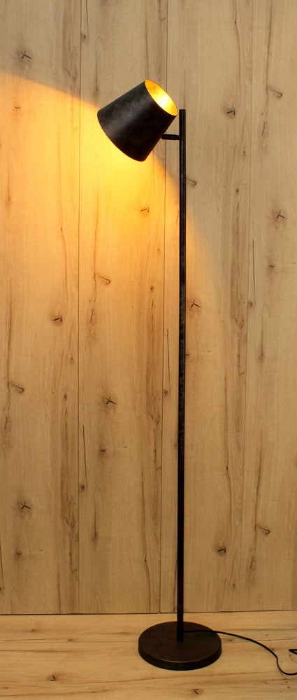 Lampadaire éclairé posé sur un parquet clair, halo jaune projeté au mur