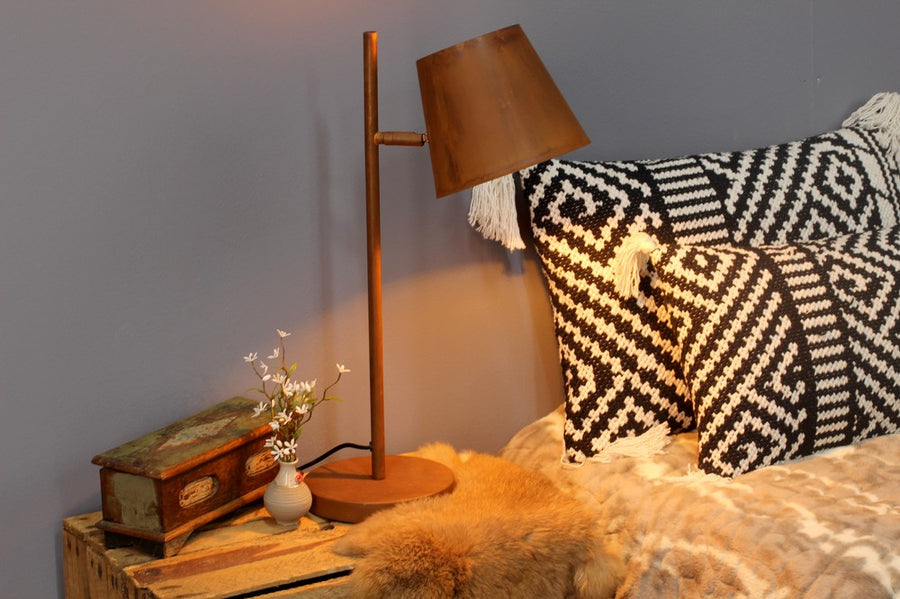 Gros plan de la lampe allumée près de coussins à motifs et d’une peau