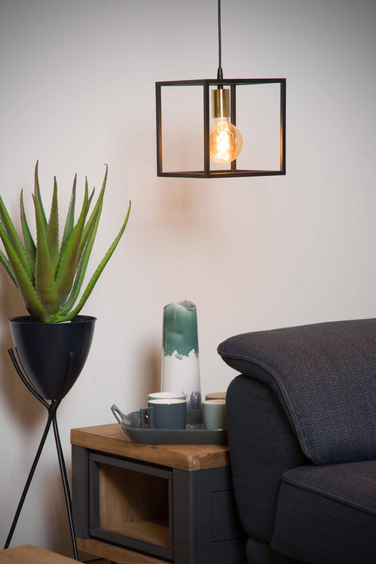 Mise en ambiance du luminaire près d'une plante et d'un canapé gris