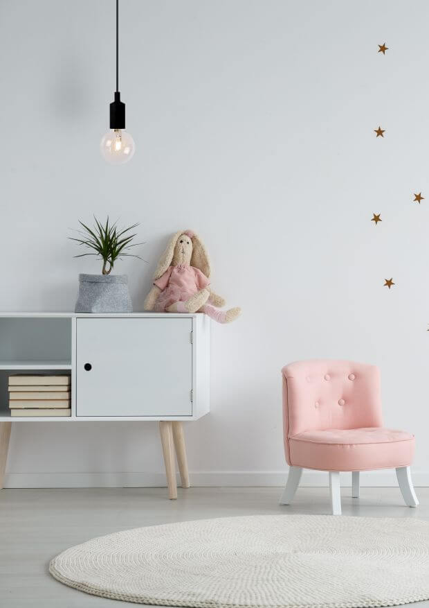 Vue rapprochée de la suspension noire suspendue devant un mur blanc étoilé avec mobilier enfantin.