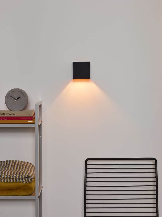 Mise en ambiance : applique murale noire éclairant un mur blanc vers le bas