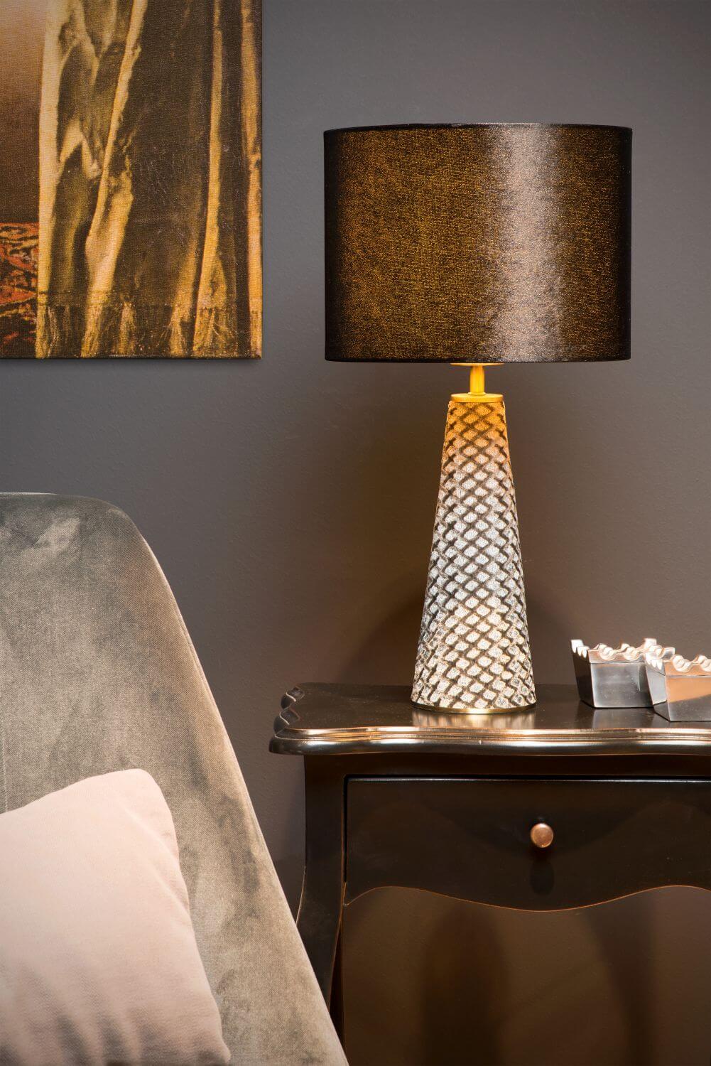 Ambiance de chambre avec lampe allumée près d'un lit et d'un tableau.